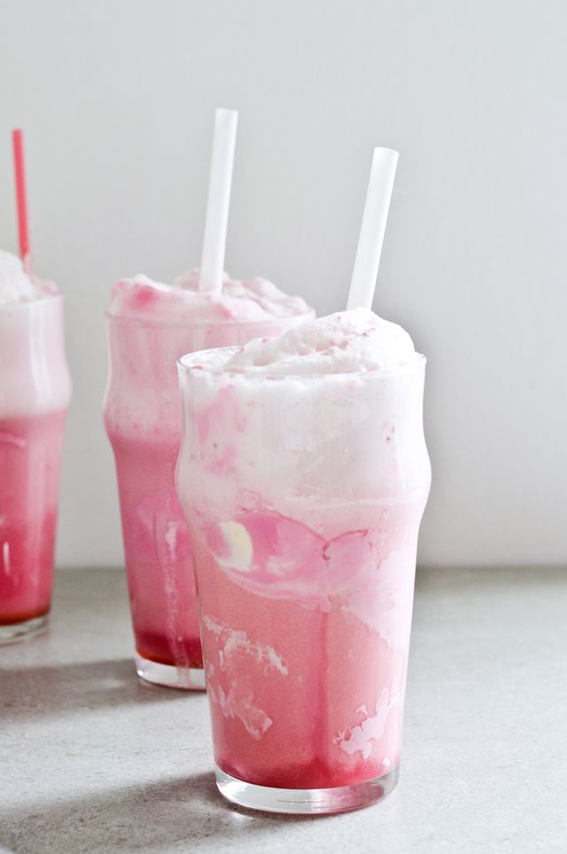 two glasses filled with ice cream and pink liquid on top of a counter next to each other