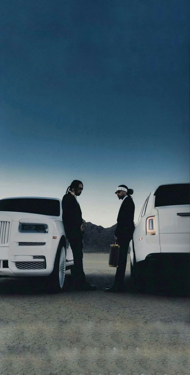 two men standing next to their cars in the desert