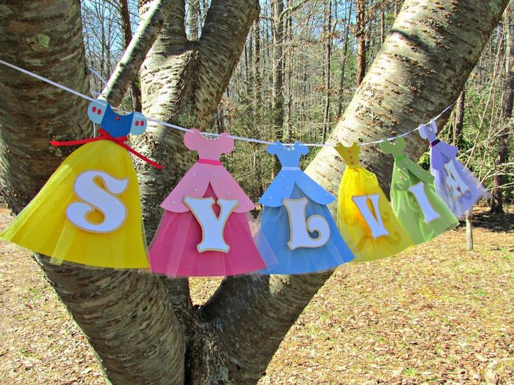 a colorful banner hanging from a tree in the woods with name spelled on it,