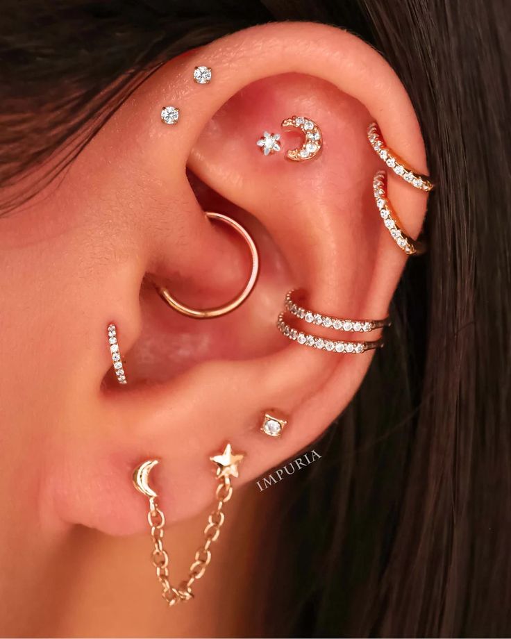 a woman wearing ear piercings with stars, moon and crescent designs on her ears