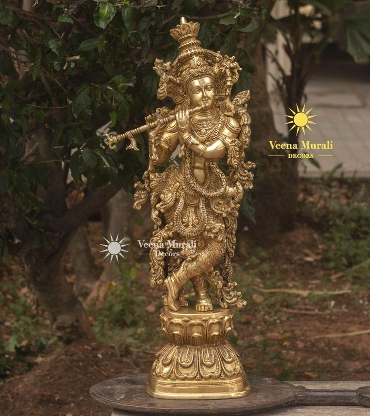 a golden statue is sitting in the middle of a garden with trees and bushes behind it