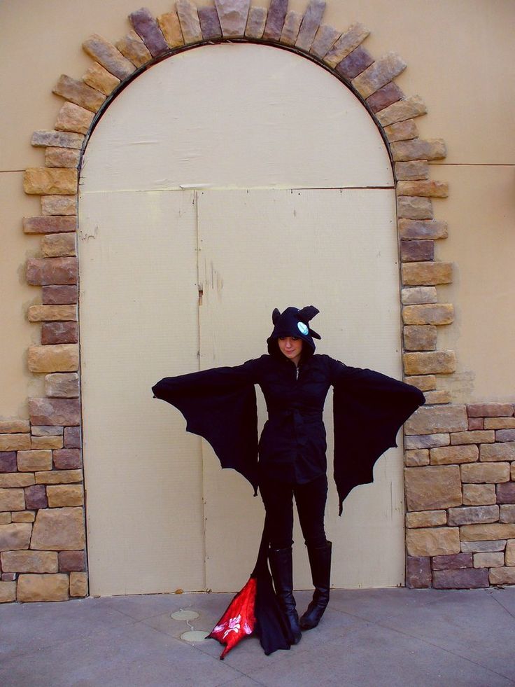 a woman dressed as a bat standing in front of a door