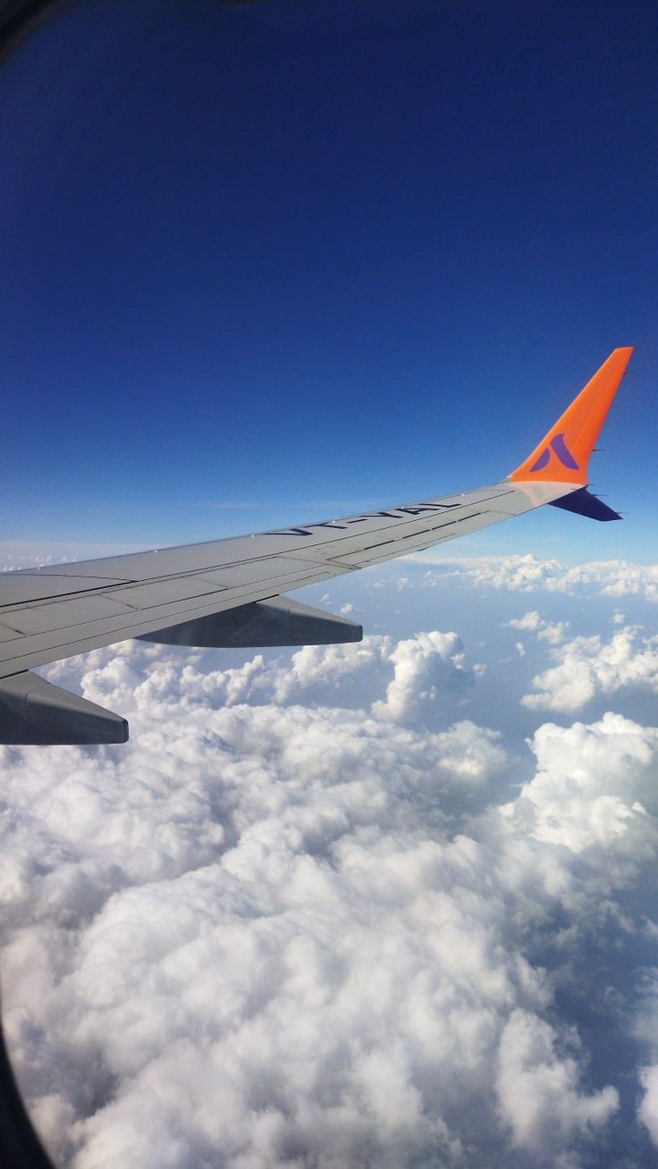 the wing of an airplane flying over clouds