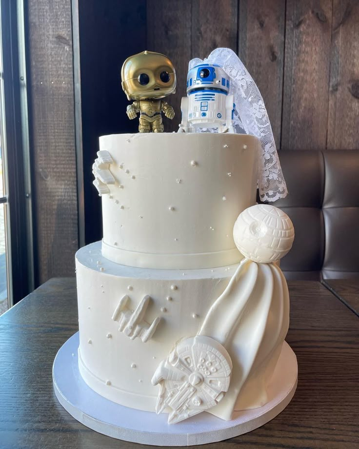 a star wars themed wedding cake with a robot figurine on the top tier