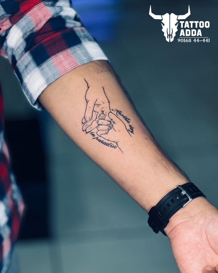 a person with a tattoo on their arm holding the hand of another person's wrist