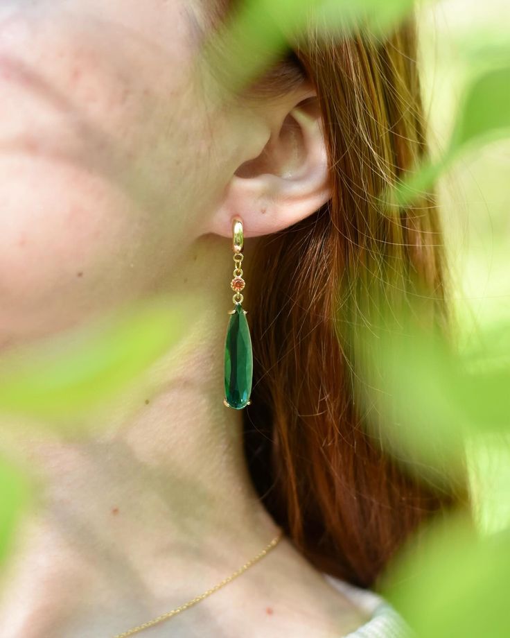 a woman with red hair wearing green earrings