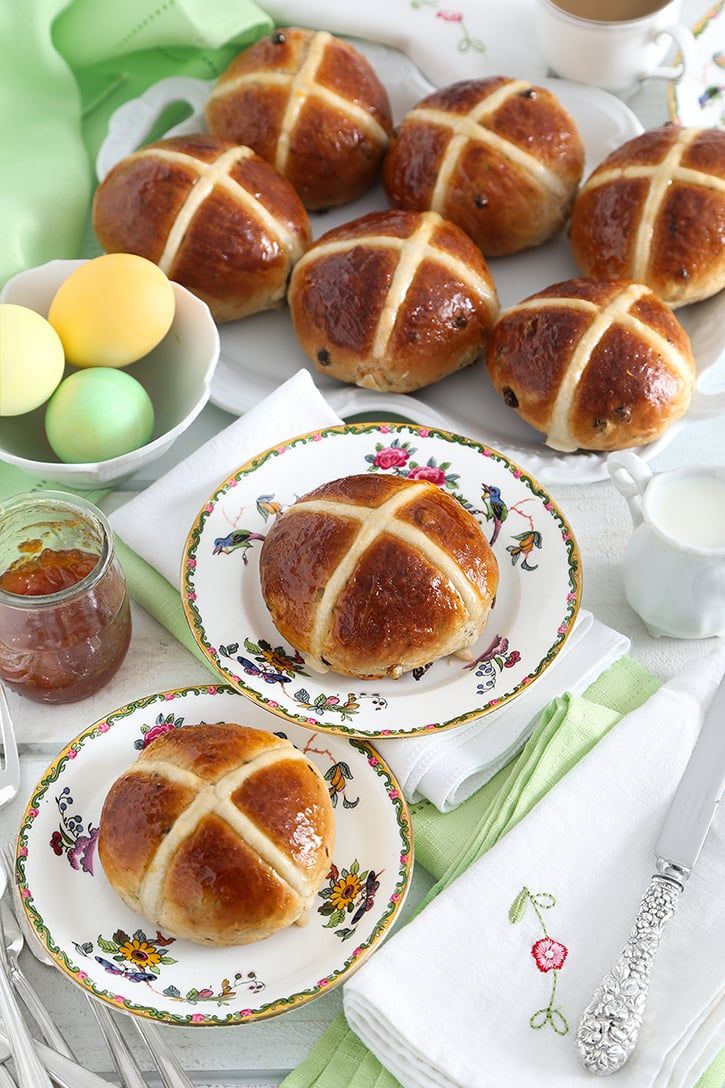 hot cross buns on plates next to some eggs