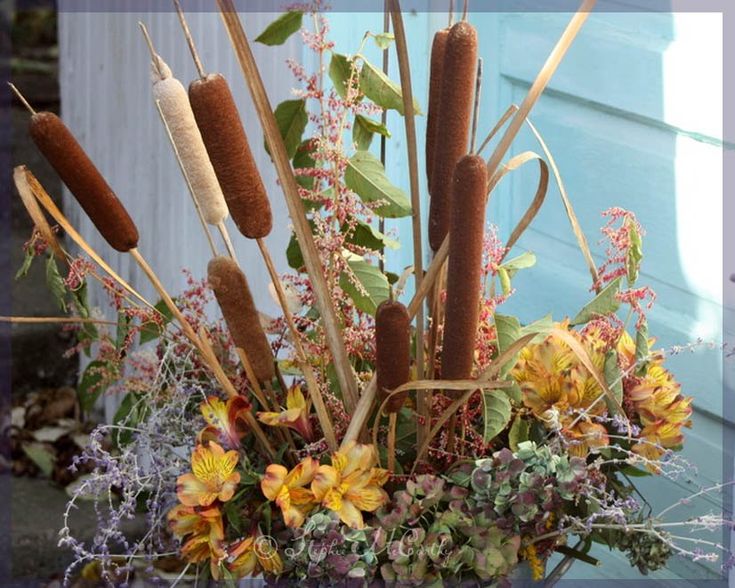 a vase filled with lots of flowers next to a blue door and window sill