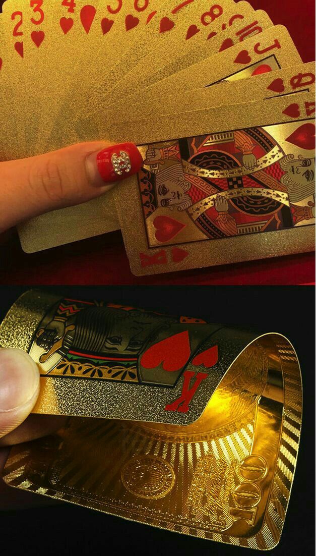 a hand holding four playing cards in front of a gold card holder with diamonds on it