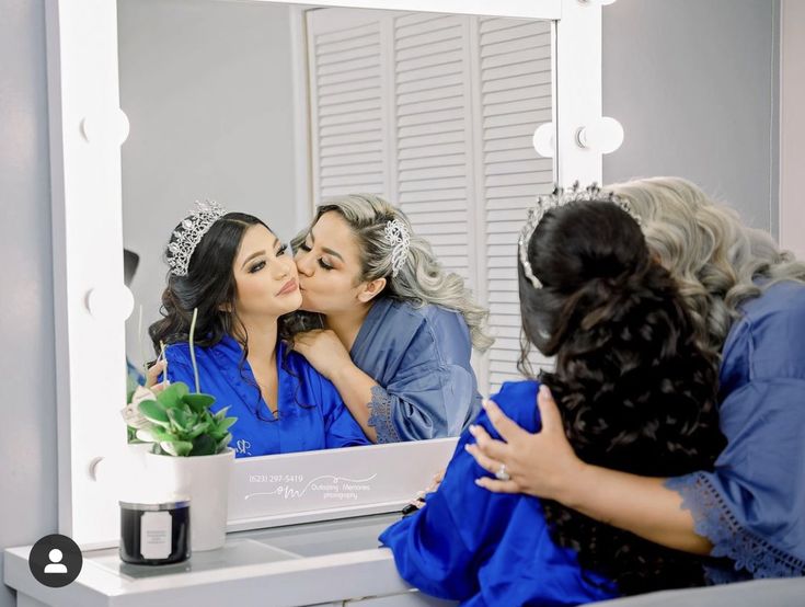 a woman kissing another woman's face in front of a mirror