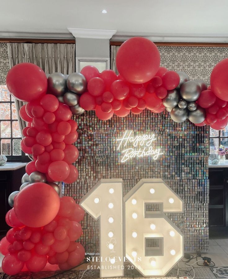 a large balloon arch with the number sixteen surrounded by red, silver and white balloons