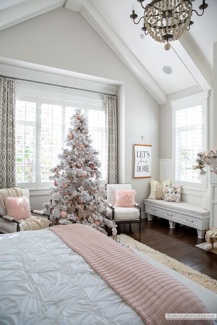 a white christmas tree is in the corner of a bedroom