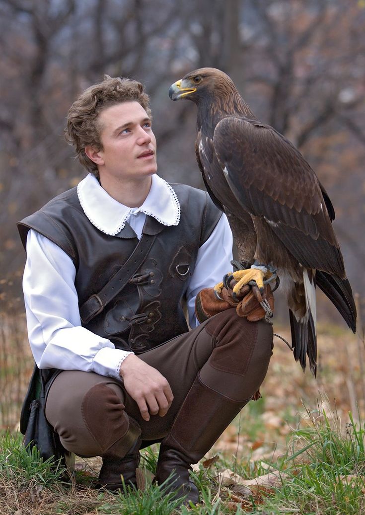 a man kneeling down with a bird on his arm