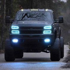 a black truck with lights on driving down the road