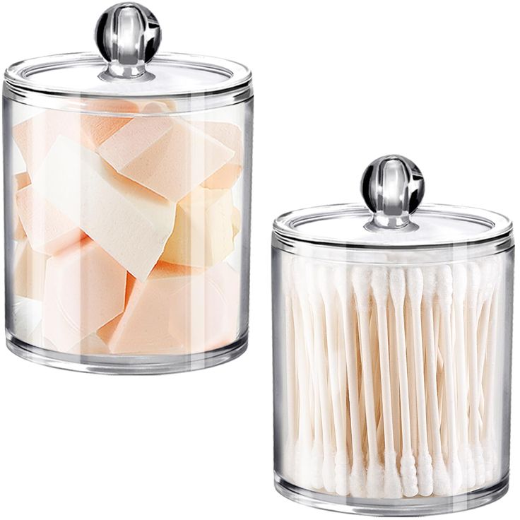 two glass canisters filled with toothbrushes on top of a white surface