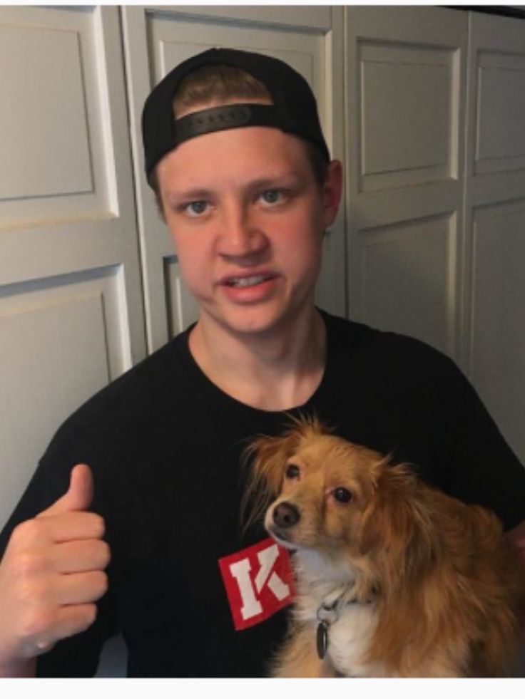 a man holding a dog in his arms and giving the thumbs up sign with both hands