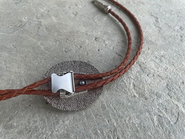 This awesome bolo tie has a southwestern design and agate centerpiece. The cord is genuine brown leather.Our bolos pair nicely with many of our belt buckles! They make wonderful gifts. The western bolo tie rope length is 39'' ; charm agate stone pendant size is 2'' x 1 1 /2'' Southwestern Style Adjustable Bolo Ties, Brown Concho Jewelry For Rodeo, Southwestern Silver Jewelry With Adjustable Cord, Rustic Brown Jewelry For Rodeo, Adjustable Concho Lariat Jewelry, Adjustable Southwestern Jewelry With Cord, Adjustable Cord Jewelry For Western-themed Events, Brown Lariat Jewelry With Adjustable Cord, Adjustable Western Bolo Tie With Concho