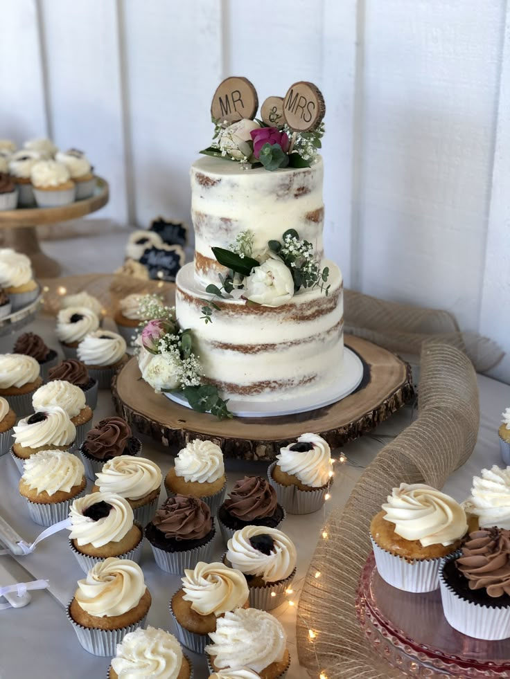 a wedding cake and cupcakes on a table