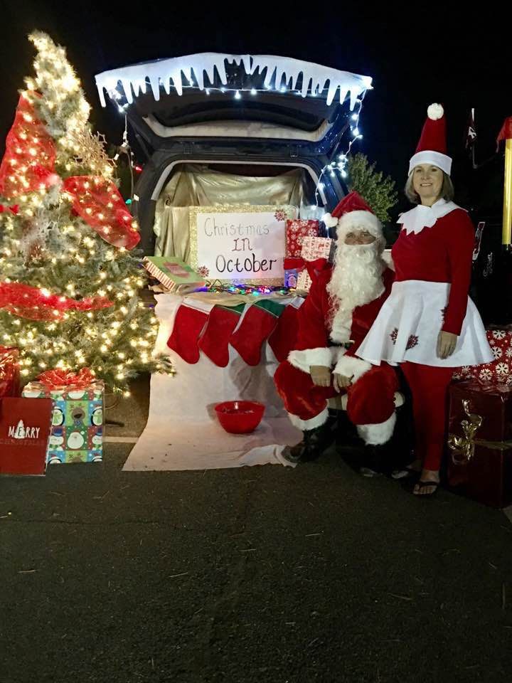 two people dressed as santa clause and mrs claus in front of a christmas tree with presents