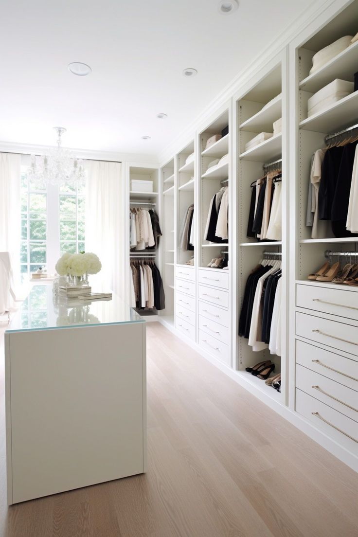 a walk in closet filled with lots of white drawers and shelves next to a window