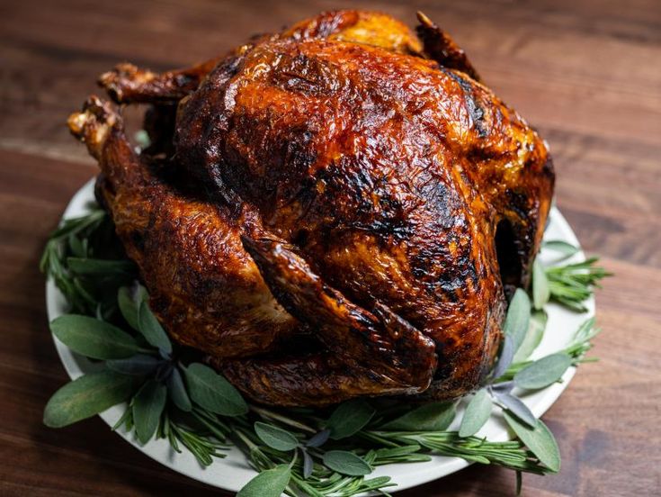 a roasted turkey on a plate with fresh herbs