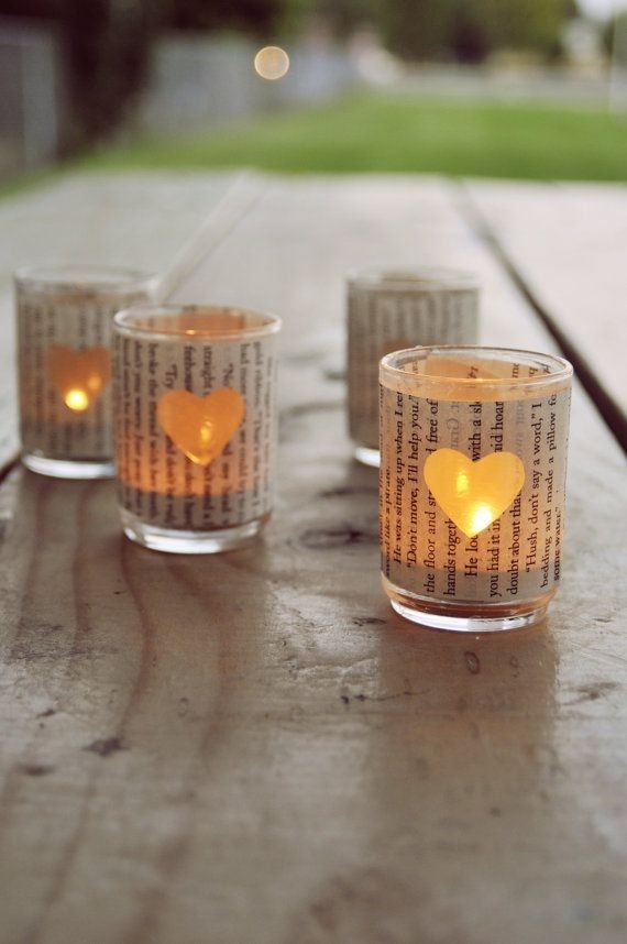 three candles are sitting on a table with newspaper pages in the shape of a heart