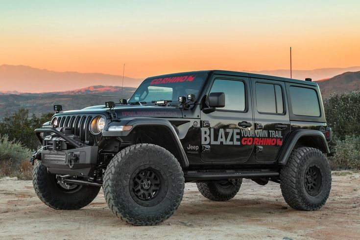 a black jeep parked on top of a dirt field