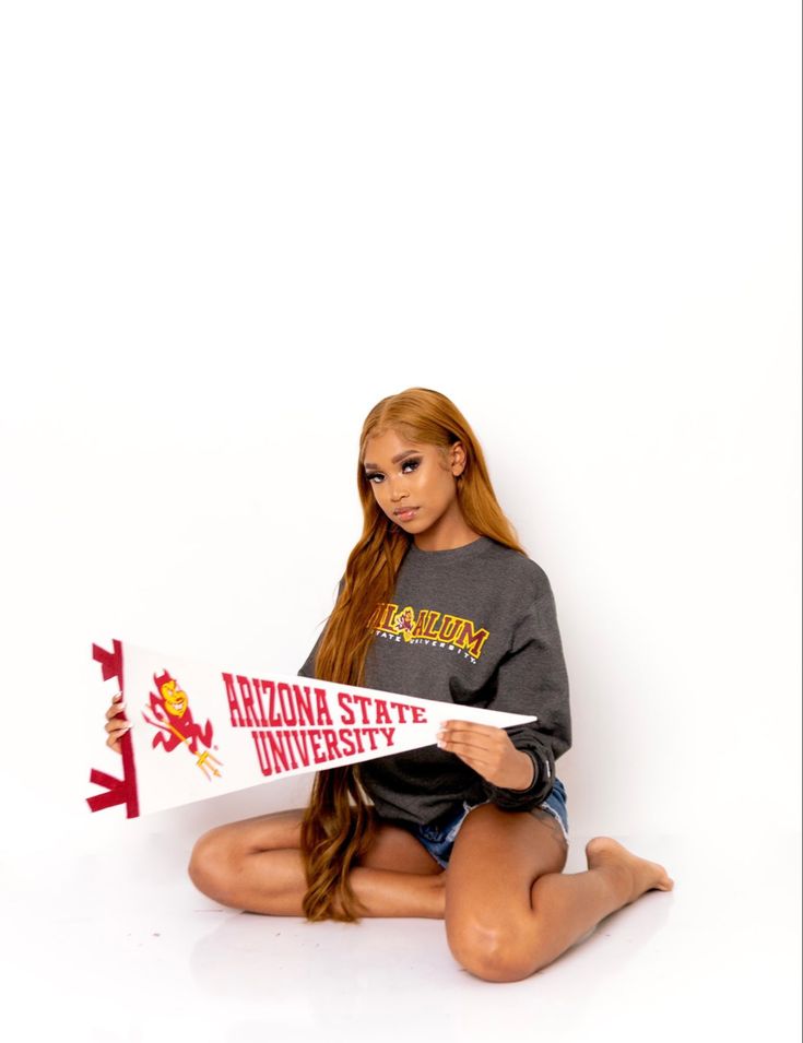 a woman sitting on the floor holding a sign that says arizona state university in front of her