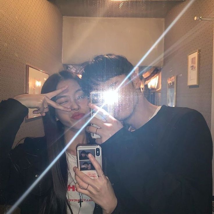 a man and woman taking a selfie in front of a mirror