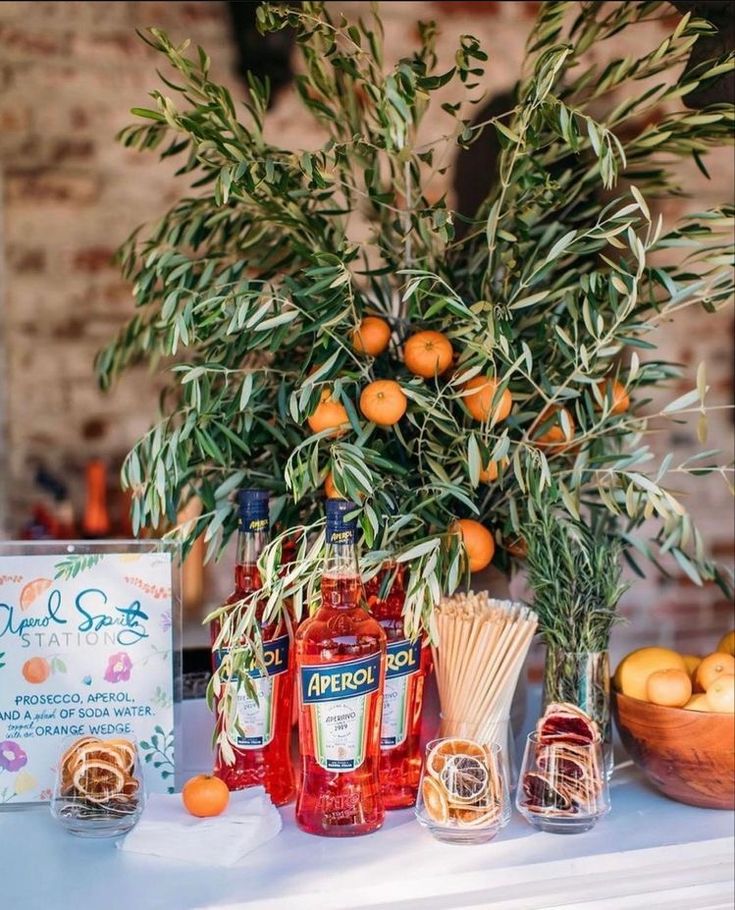 an arrangement of liquor bottles and oranges on a table with a sign in the background