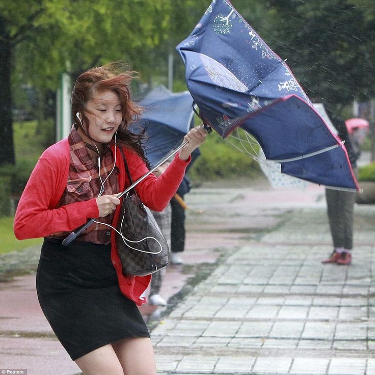 a woman holding an umbrella and listening to music on her headphones while walking in the rain