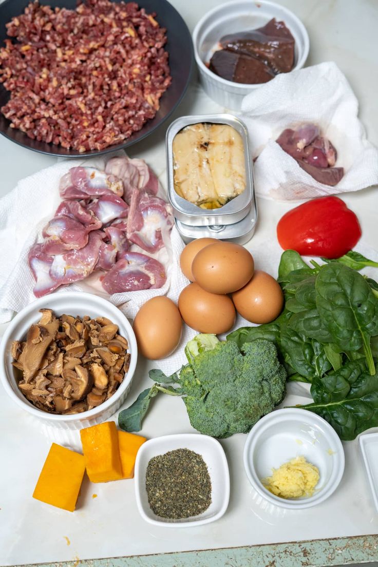 an assortment of ingredients are laid out on a counter top, including eggs, broccoli, cheese, and meat