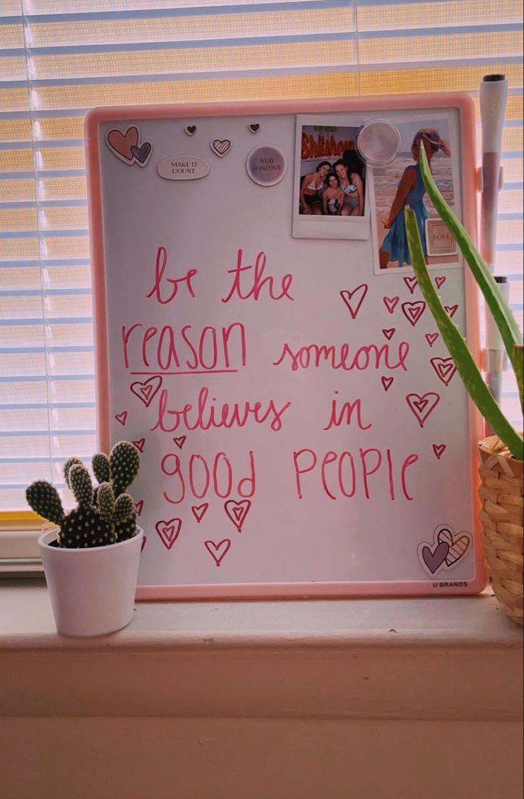 a white board with writing on it next to a potted cactus