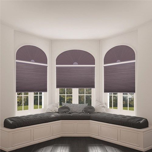 a room with three windows and a couch in the corner, all decorated in shades of purple