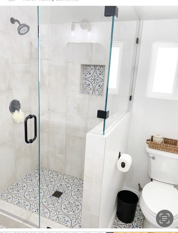 a bathroom with a glass shower door and tiled floor