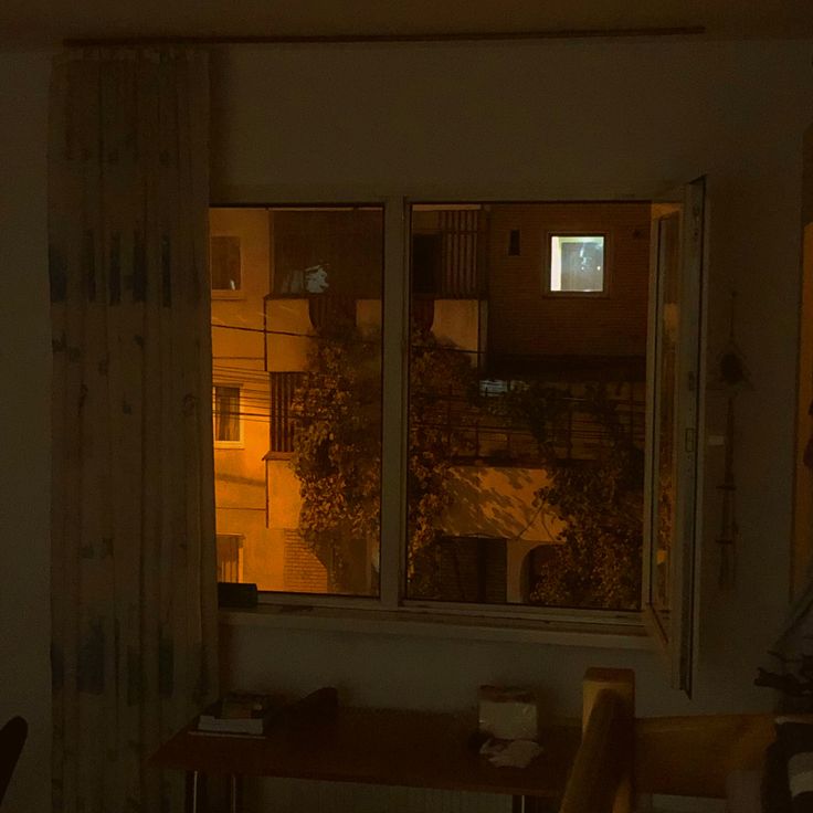 an empty room with a window that is lit up at night and the curtains are open