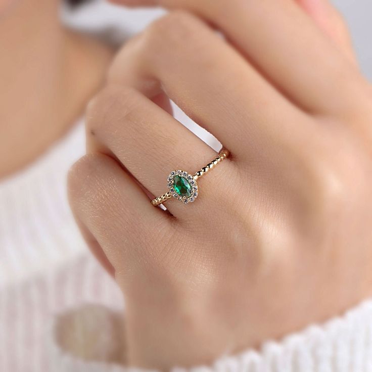 a woman's hand wearing a ring with an emerald stone and diamond band on it