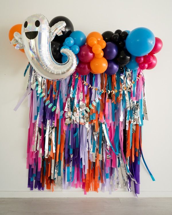 balloons and streamers are hanging on the wall with an elephant balloon attached to it