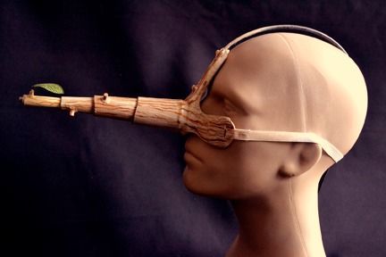 a head with a piece of wood sticking out of it's side and wearing a blindfold