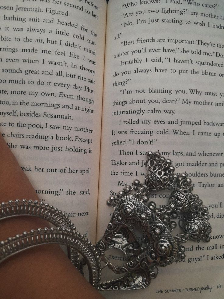 a close up of a person's hand holding an open book with jewelry on it