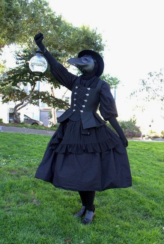 a woman in a black dress and hat holding a frisbee on the grass