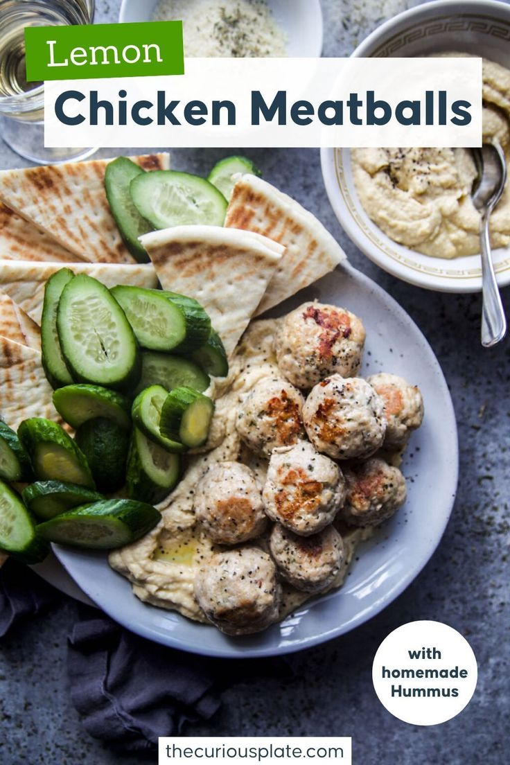 chicken meatballs with hummus and cucumbers on a white plate next to pita bread