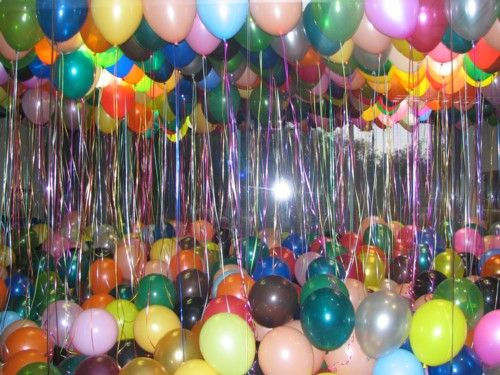 a room filled with lots of balloons and streamers