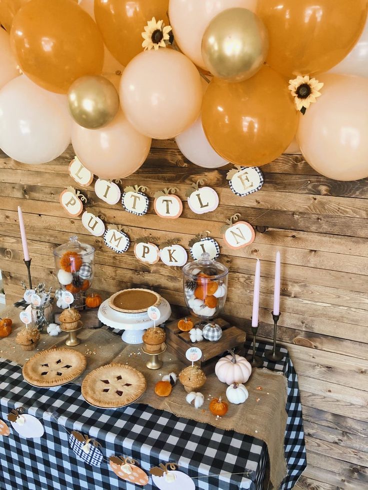 a table topped with cookies and pies next to balloon filled wall hanging from the ceiling