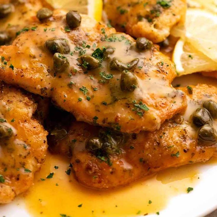 chicken with capers and lemon slices on a white plate, ready to be eaten