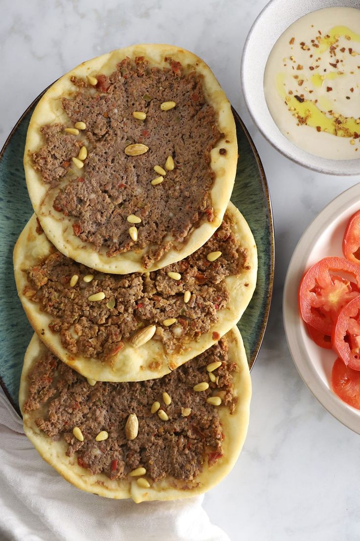 three pita breads on a plate with tomatoes and yogurt