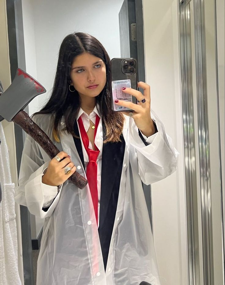 a woman is taking a selfie in the mirror while holding a hammer and cell phone