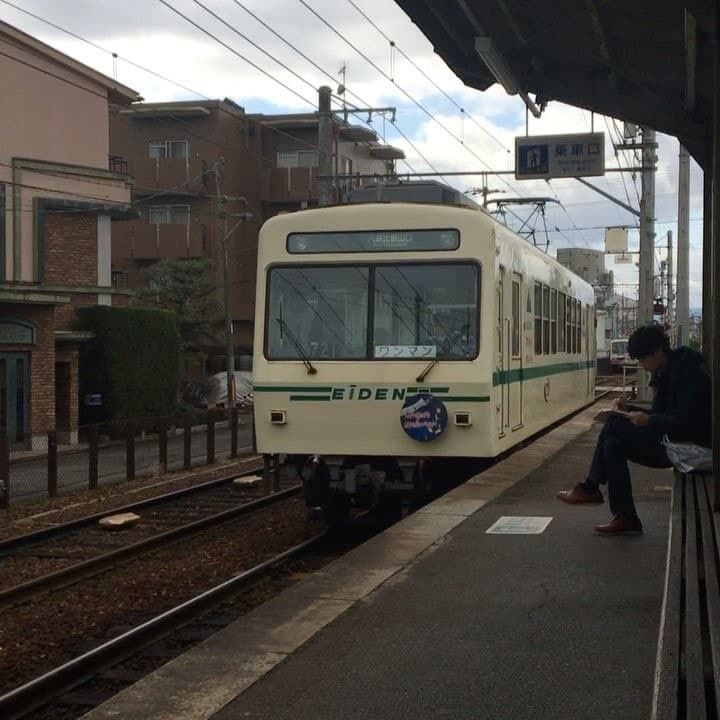 a man sitting on the side of a train station platform next to a white train