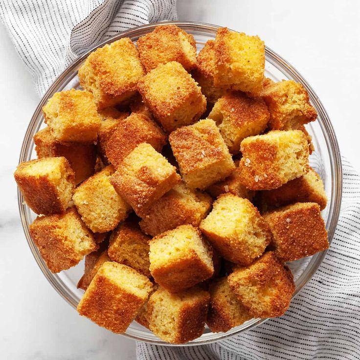 a glass bowl filled with bread cubes on top of a white and gray towel