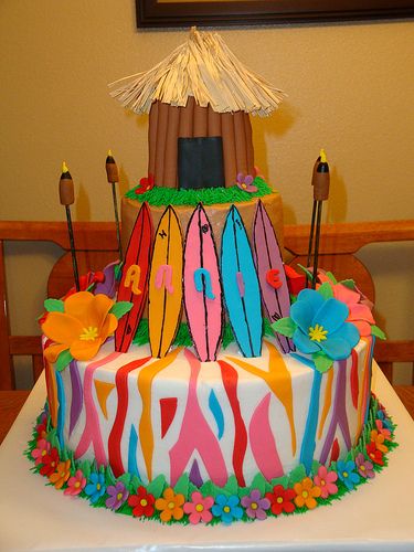 a cake decorated with surfboards and flowers on a table